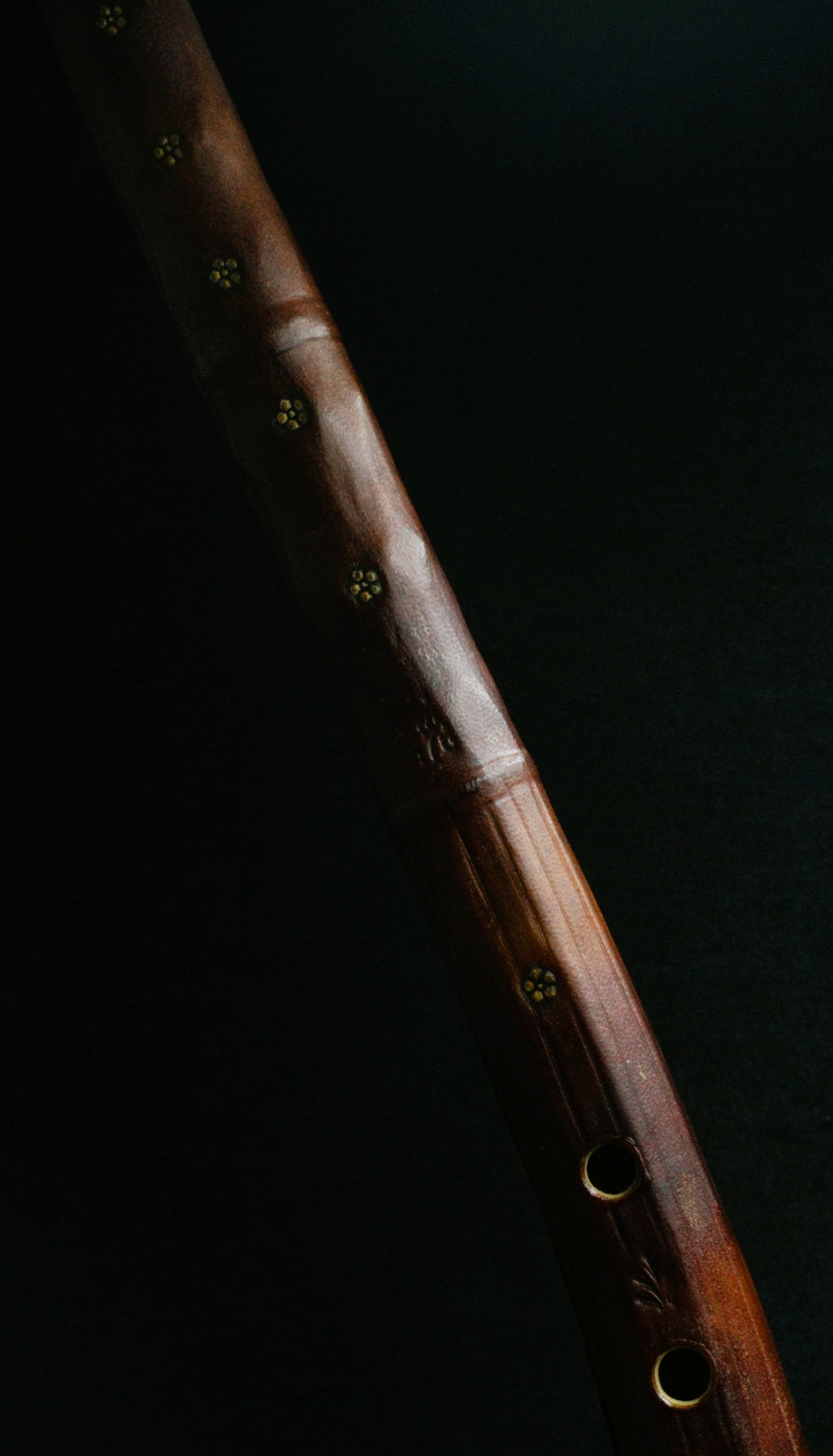 Détail macro d'un cornet à bouquin (cornetto) — bois sculpté, trous incrustés dorés, gainé de parchemin